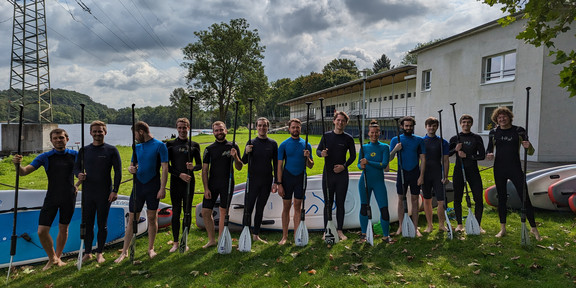 Group members with paddles in their hands in front of SUPs