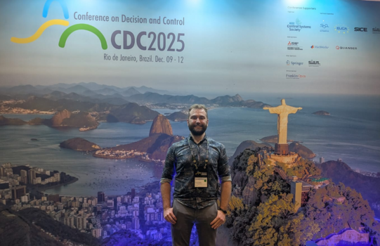 Manuel standing in front of the conference banner, depicting Cristo Redentor.